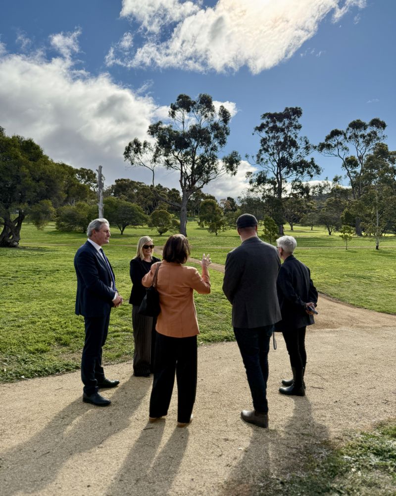 The Governor speaks with a group of people outdoors in a parkland space