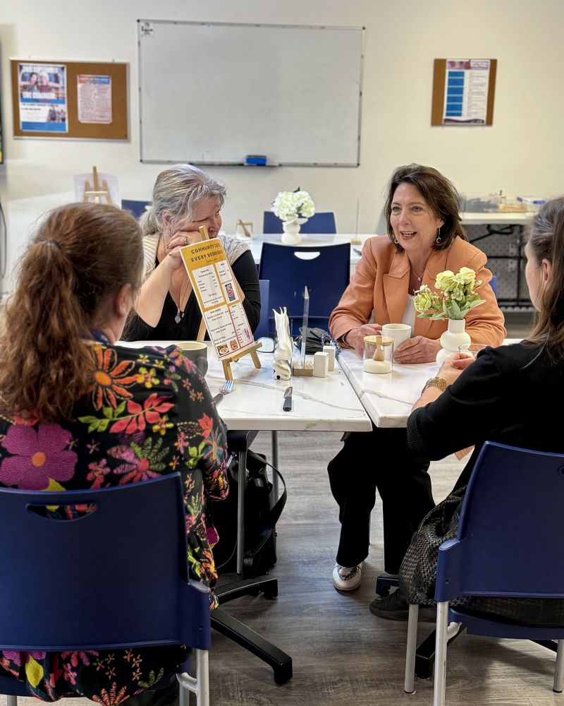 The Governor sits at a cafe table and chats with three women