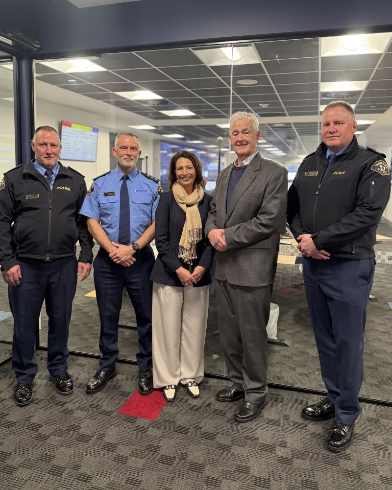 The Governor and Dr Walters stand indoors with three Tasmania Police officers. Everyone is looking at the camera and smiling.