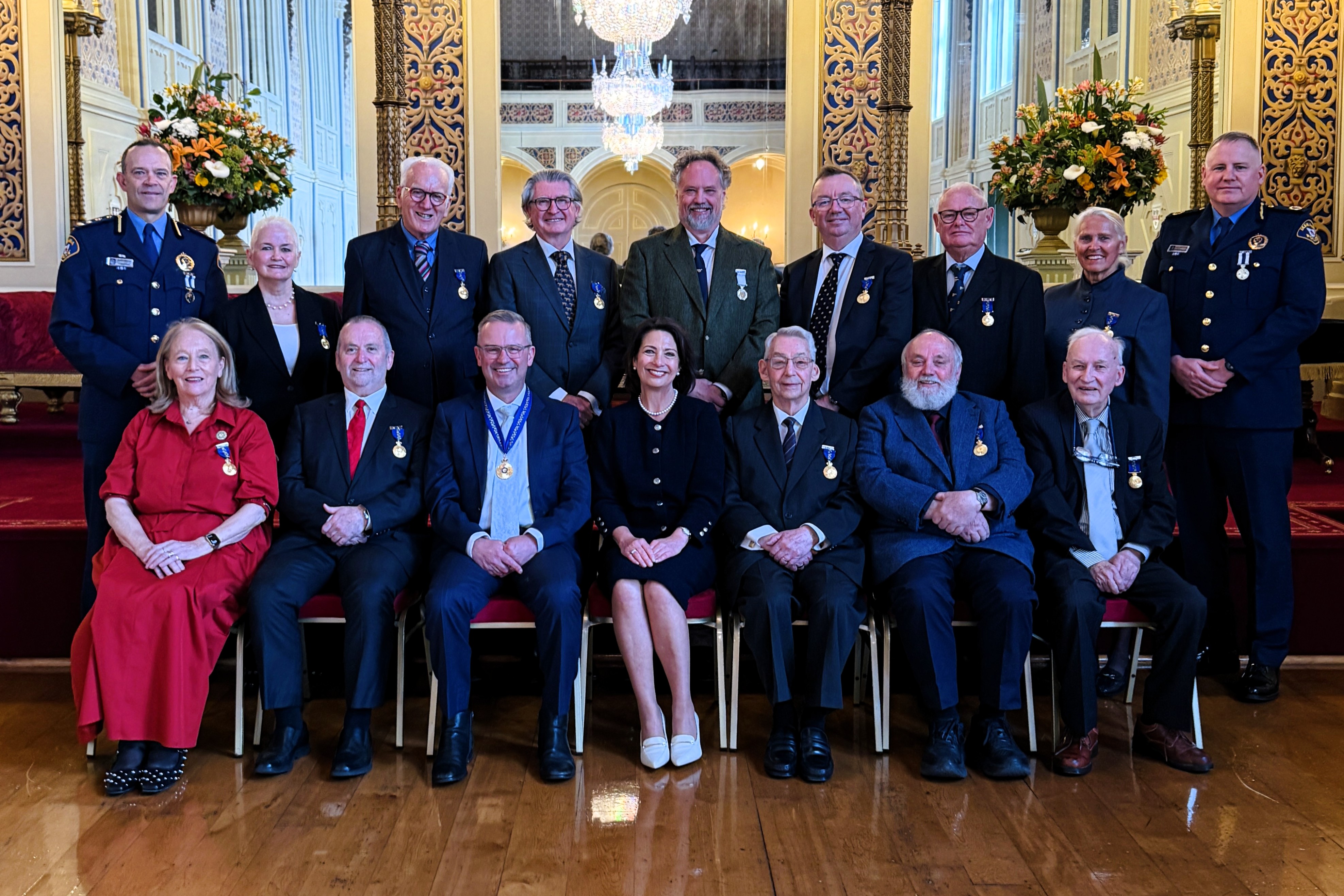 The Governor sits with a group of 15 people in the Government House ballroom