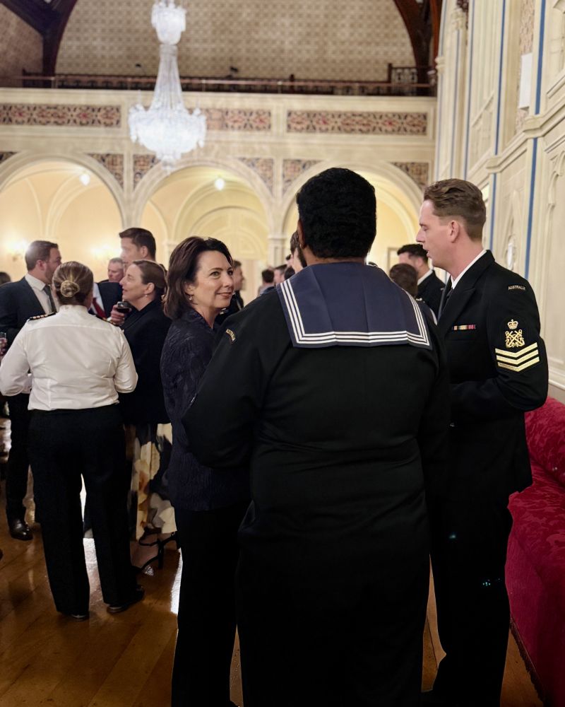 The Governor stands in the Government House ballroom and speaks with a group of people wearing Royal Australian Navy uniforms