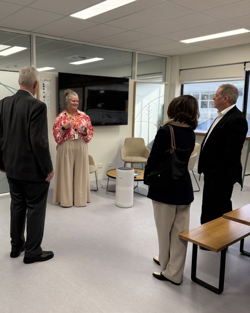 The Governor and Dr Walters stand indoors in a kitchen area talking with a man and a woman