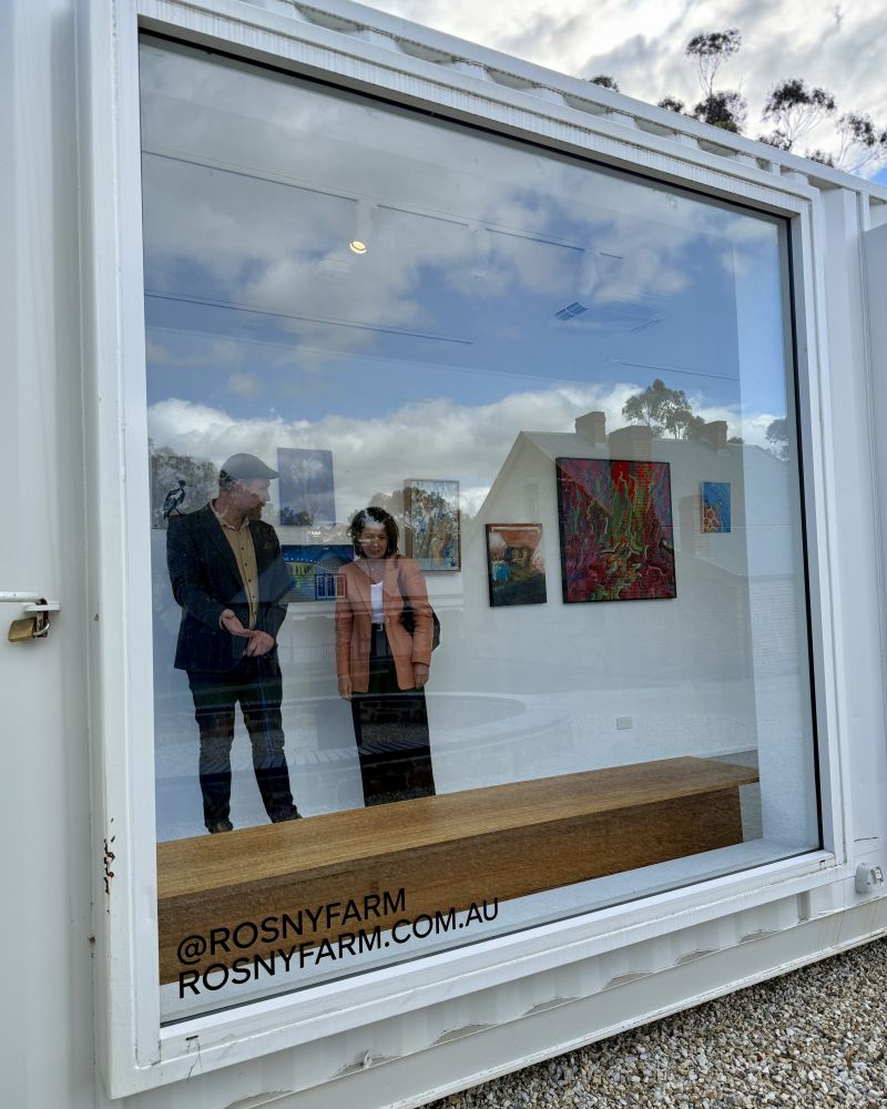 The Governor stands inside a shipping container art gallery next to a man who is showing her the space