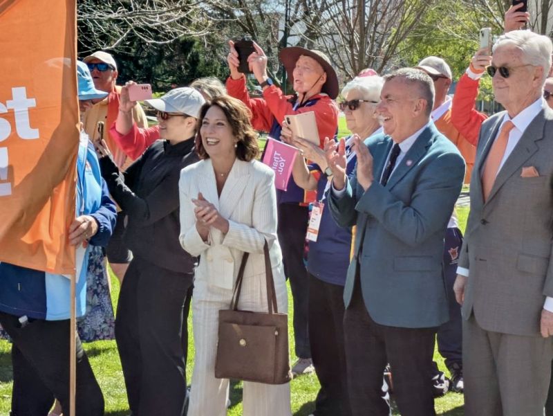 The Governor is outdoors applauding as she watches a parade of athletes walk past