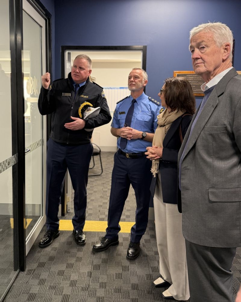 The Governor and Dr Walters stand indoors listening to two Tasmania Police officers speak