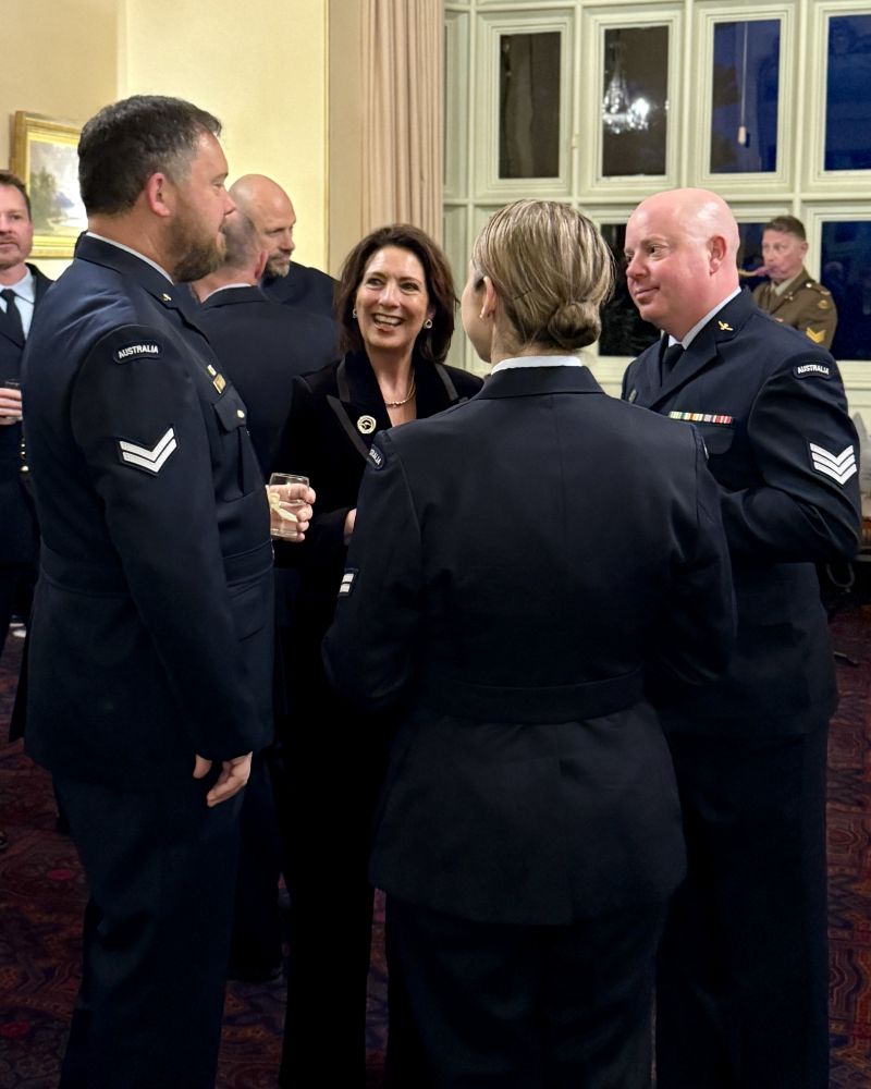 The Governor stands with a group of people in RAAF uniform in the Government House Drawing Room