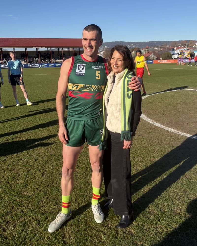 The Governor stands next to a Tasmanian Devils VFL player on the pitch at North Hobart Oval