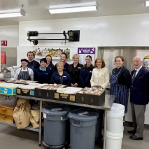 Her Excellency, Professor Chalmers and a group of people standing in the Government House kitchen