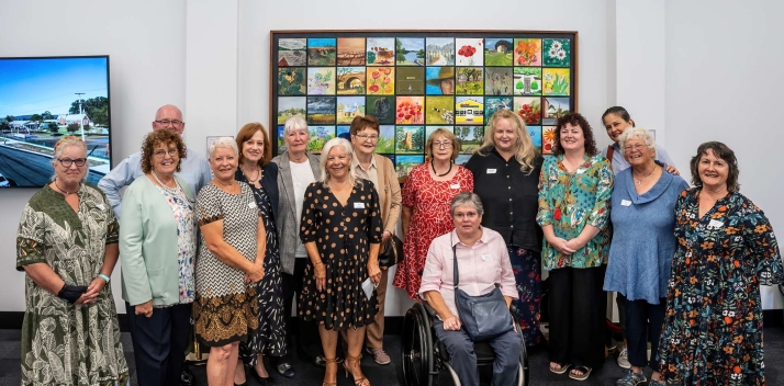 Her Excellency posing with a group of people in front of a colourful artwork