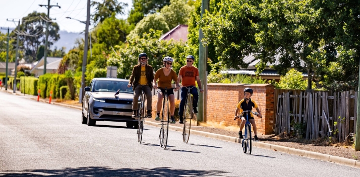 Four penny farthing bicycles riding in front of the vice-regal vehicle at Evandale
