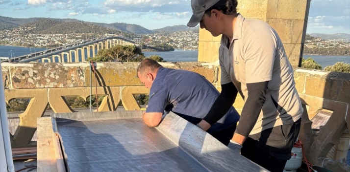 Two men working with lead on the roof of the Clock Tower