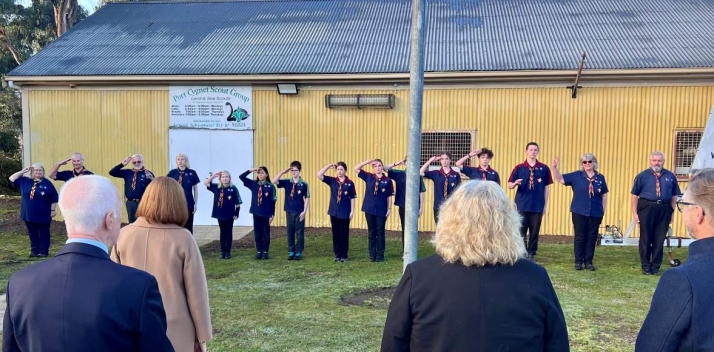 The Governor standing outdoors taking the salute from a line-up of Scouts