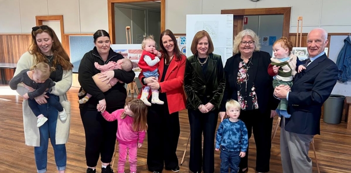 The Governor and Professor Chalmers with a group of mothers and toddlers, who are all smiling at the camera
