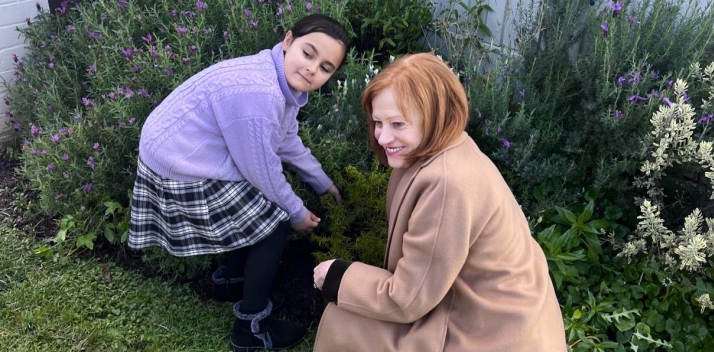 The Governor and a young girl planting a rosemary bush in a garden