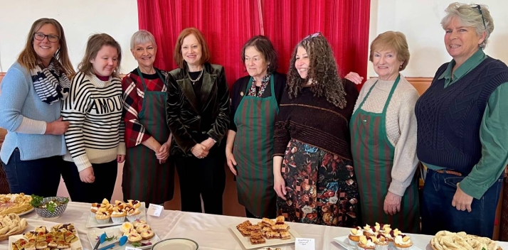 The Governor standing with a group of women in front of a table of cakes