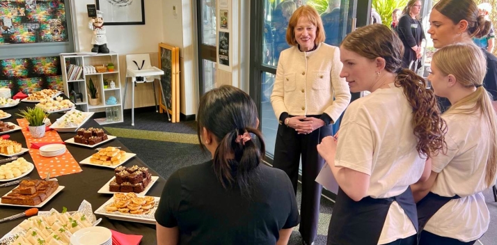 Her Excellency speaking to school students near a display of food