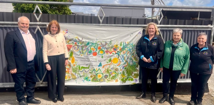 Her Excellency and four other people with a welcome banner